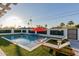 A backyard pool with an orange umbrella, surrounded by lounge chairs and lush landscaping at 8522 E Virginia Ave, Scottsdale, AZ 85257