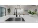 Kitchen island sink up-close, with white cabinets, white countertops, and a view to the dining room at 8522 E Virginia Ave, Scottsdale, AZ 85257