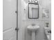 A compact powder room featuring a pedestal sink, decorative mirror, and paneled accent wall at 1104 E Tekoa Ave, Gilbert, AZ 85298