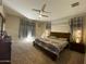 Bright bedroom with ceiling fan, soft carpet, and two windows with decorative curtains at 11562 W Levi Dr, Avondale, AZ 85323