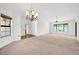 Open-concept living room featuring neutral carpet, vaulted ceilings, chandelier, and plenty of natural light at 14151 W Yosemite Dr, Sun City West, AZ 85375
