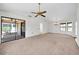 Bright living room with neutral carpet, vaulted ceilings, ceiling fan, and sliding glass doors leading to a screened-in patio at 14151 W Yosemite Dr, Sun City West, AZ 85375