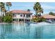 Waterfront backyard with a boat speeding across the lake in front of a Spanish-style home with palm trees at 1539 W Laurel Ave, Gilbert, AZ 85233