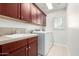 A well-lit laundry room with dark wood cabinets, a utility sink, and a stacked washer and dryer at 1550 S Chaparral Blvd, Gilbert, AZ 85296