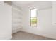 Walk-in closet featuring built-in white shelves, carpeted floor, and a window with a neighborhood view at 1550 S Chaparral Blvd, Gilbert, AZ 85296