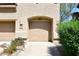 Attached tan garage featuring an arched entrance, concrete driveway and desert landscaping at 16420 N Thompson Peak Pkwy # 2020, Scottsdale, AZ 85260