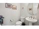 Well-lit powder room featuring a pedestal sink, toilet, and decorative wall art at 16946 W Vernon Ave, Goodyear, AZ 85395