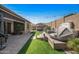 Lush backyard featuring a hot tub, seating area, artificial turf, and a brick-paved patio at 18970 W Desert Hills Dr, Surprise, AZ 85388