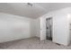 A bedroom with light carpet leads to an open door to a laundry area with a washing machine at 201 S Greenfield Rd # 129, Mesa, AZ 85206