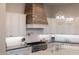 Close up of a modern kitchen featuring a wooden hood, stainless steel appliances, and gray countertops at 20213 W Amelia Ave, Buckeye, AZ 85396