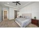 Cozy main bedroom featuring a tray ceiling, ceiling fan, and en suite bathroom at 20213 W Amelia Ave, Buckeye, AZ 85396