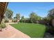 Well-manicured backyard features lush green grass, mature trees, and a brick patio, creating a serene outdoor space at 20959 W Western Dr, Buckeye, AZ 85396