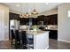 Kitchen featuring dark cabinets, granite countertops, stainless steel appliances, a kitchen island with seating and pendant lighting at 20959 W Western Dr, Buckeye, AZ 85396