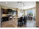 Open kitchen featuring dark cabinets, granite countertops, pendant lighting, island with seating and an adjacent dining area at 20959 W Western Dr, Buckeye, AZ 85396