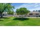 Spacious backyard with a lush lawn, mature trees and shrubs, patio, and neutral-colored siding at 21222 N Aurora Dr, Sun City West, AZ 85375
