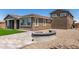 Backyard with fire pit, gravel, block patio, and artificial grass, with view of the home's exterior at 22386 N Daniel Dr, Maricopa, AZ 85138