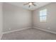 Neutral bedroom featuring gray carpet, a ceiling fan, and a window for natural light at 22386 N Daniel Dr, Maricopa, AZ 85138