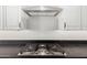 Modern cooktop stove with stainless steel vent hood, set against stylish backsplash at 22386 N Daniel Dr, Maricopa, AZ 85138