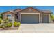 Charming single-Gathering home featuring stone accents and a three-car garage, landscaped with desert plants at 26270 W Horsham Ct, Buckeye, AZ 85396