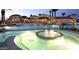 Elegant community pool at night, lit with warm lighting, alongside nearby buildings and landscaping at 26421 W Zachary Dr, Buckeye, AZ 85396