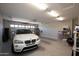 Spacious two-car garage with overhead lighting, storage shelves, and a white BMW parked inside at 26421 W Zachary Dr, Buckeye, AZ 85396