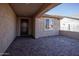Covered patio area showing stone pavers, stucco walls, and a dark-colored front door with a window at 26421 W Zachary Dr, Buckeye, AZ 85396
