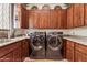 Laundry room with granite countertop, wooden cabinets, and modern appliances at 29308 N 108Th N Pl, Scottsdale, AZ 85262