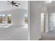 Spacious living area with neutral carpet, a ceiling fan, large windows with backyard views, and access to multiple hallways at 3531 N Sericin --, Mesa, AZ 85215