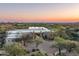 Expansive aerial view of the luxurious estate overlooking a serene lake, golf course, and distant mountains at sunset at 41611 N 113Th Pl, Scottsdale, AZ 85262