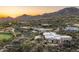 Scenic aerial view of a desert luxury estate with a pool, putting green and sunset mountain backdrop at 41611 N 113Th Pl, Scottsdale, AZ 85262