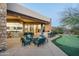 Expansive patio features an outdoor kitchen, putting green, and comfortable lounge seating, perfect for entertaining at 41611 N 113Th Pl, Scottsdale, AZ 85262