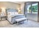 Comfortable bedroom featuring a plush bed with decorative pillows, bench, and a large window with a garden view at 5220 N Casa Blanca Dr, Paradise Valley, AZ 85253
