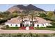 Stunning white home featuring a beautiful tile roof, palm trees, and vibrant landscaping against a mountain backdrop at 5220 N Casa Blanca Dr, Paradise Valley, AZ 85253