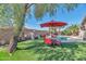 Inviting backyard featuring a pool, artificial turf, a mature tree, and a patio table with chairs at 7433 W Darrel Rd, Laveen, AZ 85339