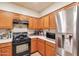 Compact kitchen with wood cabinetry, tile backsplash, and modern stainless steel appliances at 7433 W Darrel Rd, Laveen, AZ 85339