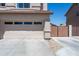Two car garage with driveway, exterior brick accents, and a view of side yard with metal fencing at 7670 W Sands Dr, Peoria, AZ 85383