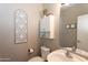 Half bathroom with decorative mirror, white vanity, and neutral-toned walls at 7670 W Sands Dr, Peoria, AZ 85383