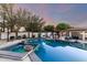 Outdoor pool and spa with decorative lighting, covered kitchen, and seating spaces at dusk at 8031 N 12Th Ave, Phoenix, AZ 85021