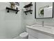 Stylish half-bath featuring a modern vanity, sleek fixtures, decorative shelving, and a convenient toilet at 8429 S 229Th Ln, Buckeye, AZ 85326