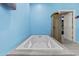 A bathtub is built into a gray-tile platform, next to a rustic cabinet with a door leading out of the room at 8429 S 229Th Ln, Buckeye, AZ 85326