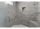 A large shower features gray tile, a built-in shelf, and built-in corner seating, with a glass door at 8429 S 229Th Ln, Buckeye, AZ 85326