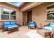 Relaxing outdoor patio area with stucco walls and stylish wicker furniture with blue pillows at 9390 W Louise Dr, Peoria, AZ 85383