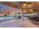 Spacious covered patio with seating, dining area, and view of the sparkling pool and lush landscaping at 18103 W Canyon Ln, Goodyear, AZ 85338