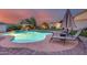 Relax by this glowing backyard pool area with palm trees and a putting green for luxurious outdoor living at 18103 W Canyon Ln, Goodyear, AZ 85338