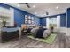 This staged bedroom boasts blue walls, a wood floor, and stylish décor at 38114 W San Clemente St, Maricopa, AZ 85138