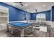 This staged game room showcases a billiards table, modern decor, and a comfortable couch at 38114 W San Clemente St, Maricopa, AZ 85138
