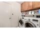 Functional laundry room with wood cabinets and modern washer and dryer at 6110 E Ivyglen St, Mesa, AZ 85205