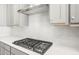 Close up of cooktop with stainless vent hood and tile backsplash at 26992 W Melinda Ln, Buckeye, AZ 85396