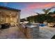 Backyard with an outdoor kitchen, pool, and covered seating under a colorful sky at 3574 E Tonto Pl, Chandler, AZ 85249