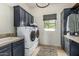 Well-organized laundry room with dark cabinetry, a utility sink, and a view to the outdoors at 36075 N Summit Dr, Cave Creek, AZ 85331